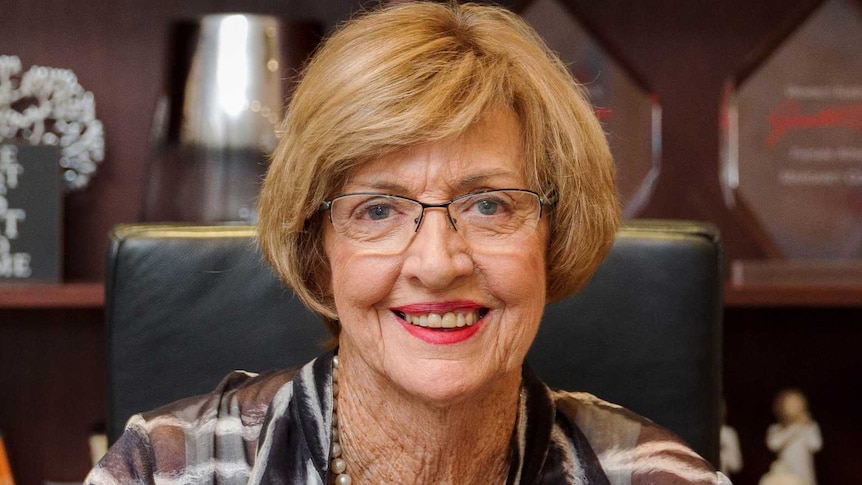 Margaret Court sits in a chair smiling at the camera.