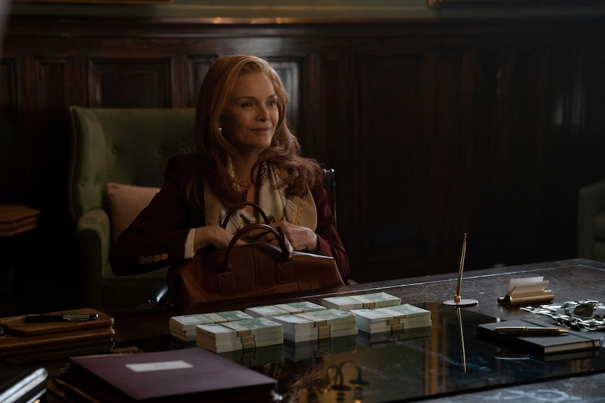 A scene from the film French Exit with Michelle Pfeiffer sitting at a desk in nice clothes