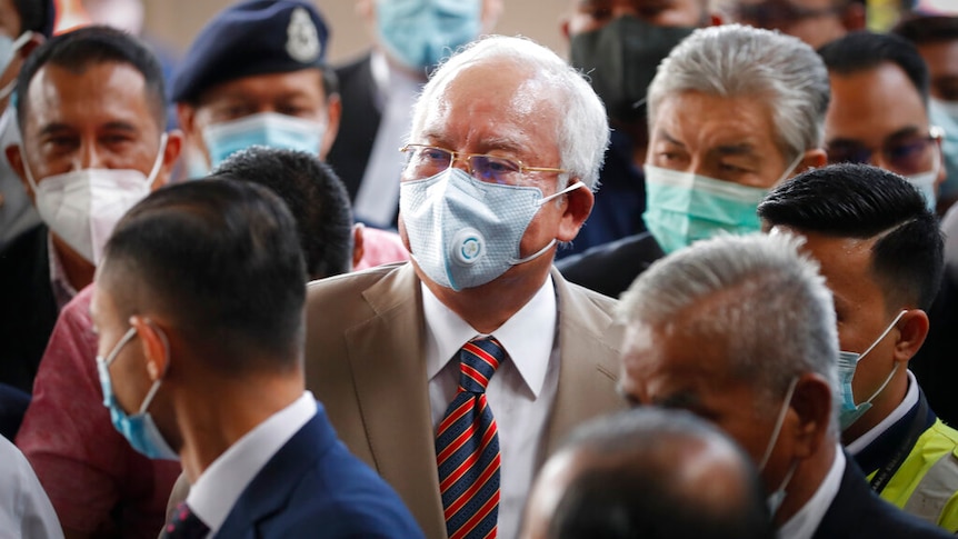 Prime Minister Najib Razak, center, wearing a face mask with his supporters arrives at courthouse in Kuala Lumpur.