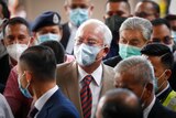 Prime Minister Najib Razak, centre, wearing a face mask with his supporters arrives at courthouse in Kuala Lumpur.