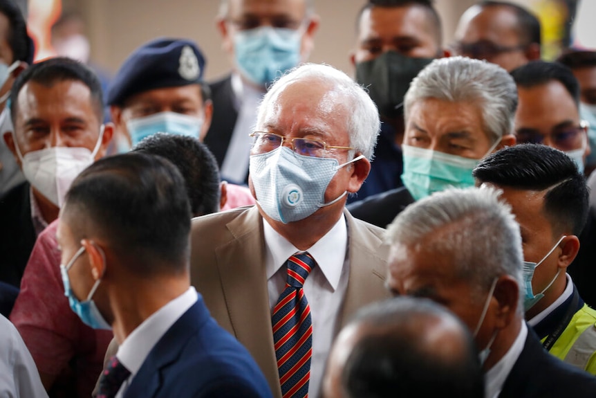 Prime Minister Najib Razak, center, wearing a face mask with his supporters arrives at courthouse in Kuala Lumpur.