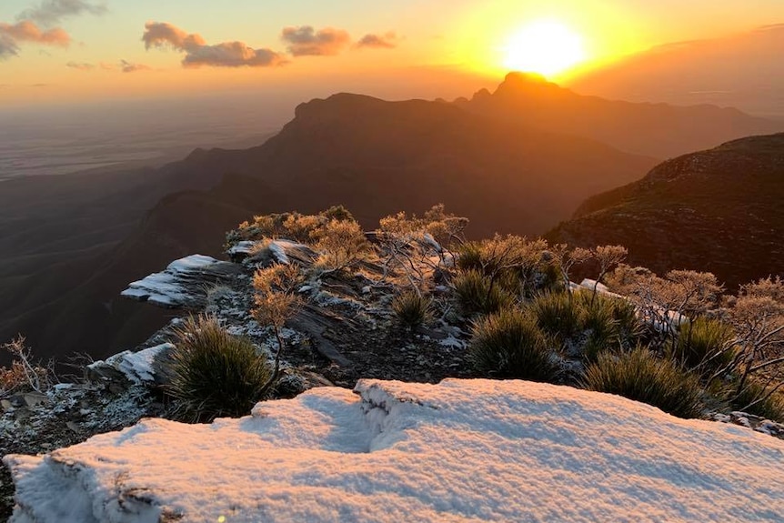 A wide shot of snow on Bluff Knoll with the sun rising over the Stirling Ranges.