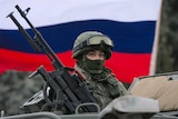 Russian flag flies behind armed serviceman in Ukraine