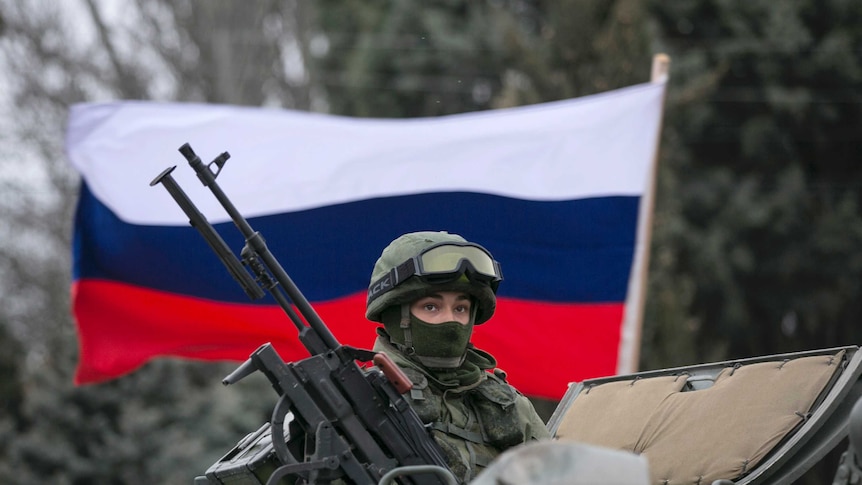 Russian flag flies behind armed serviceman in Ukraine