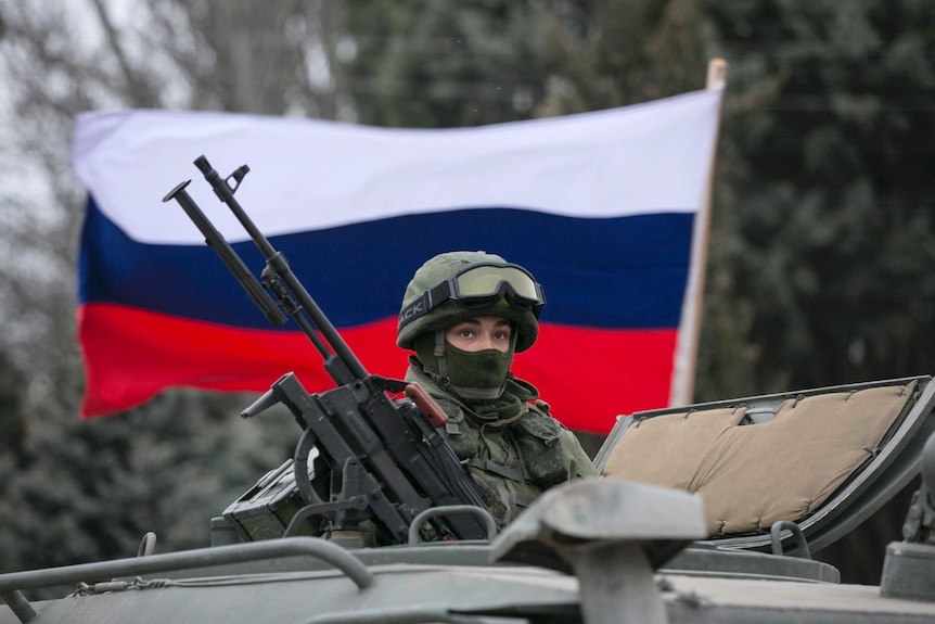 Russian flag flies behind armed serviceman in Ukraine