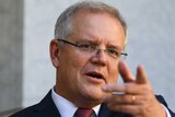 Scott Morrison stands at a podium in a courtyard and points into the distance