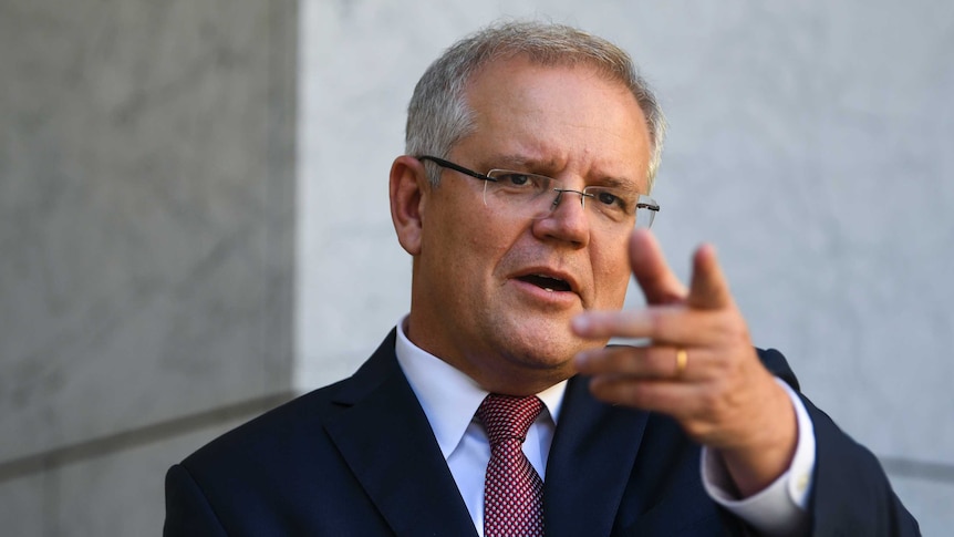Scott Morrison stands at a podium in a courtyard and points into the distance