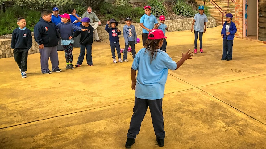 Primrary aged Aboriginal students playing handball in the school yard