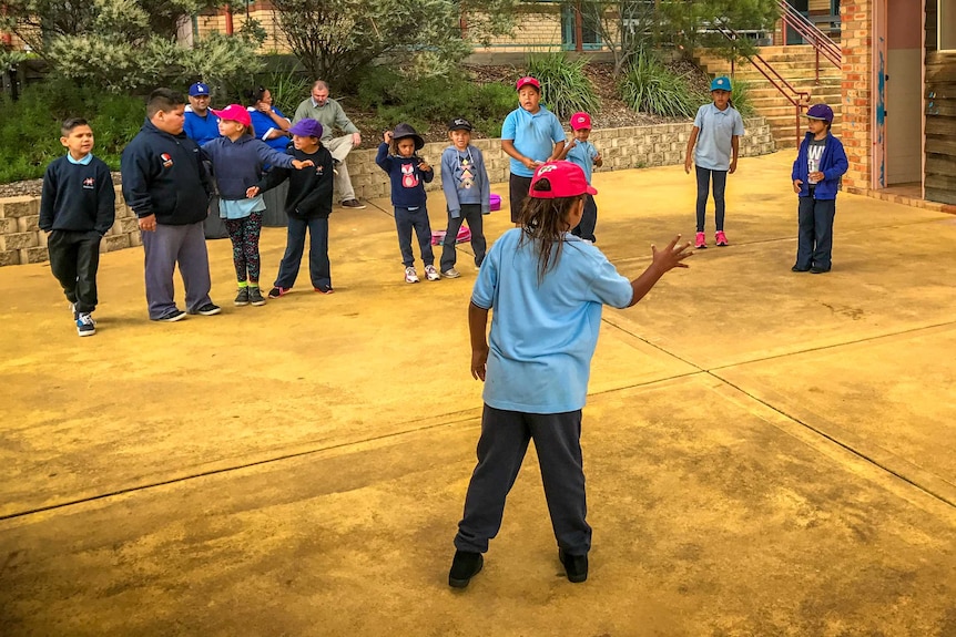 Primrary aged Aboriginal students playing handball in the school yard