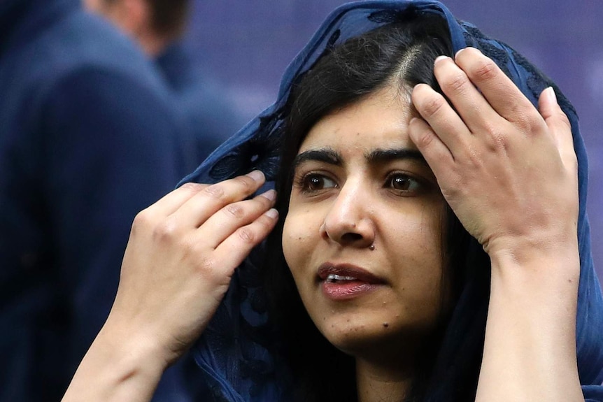 Malala Yousafzai adjusts a blue headscarf.