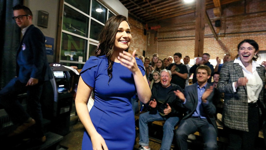 Abby Finkenauer covers her mouth with her hand as she looks overjoyed to be elected to congress.