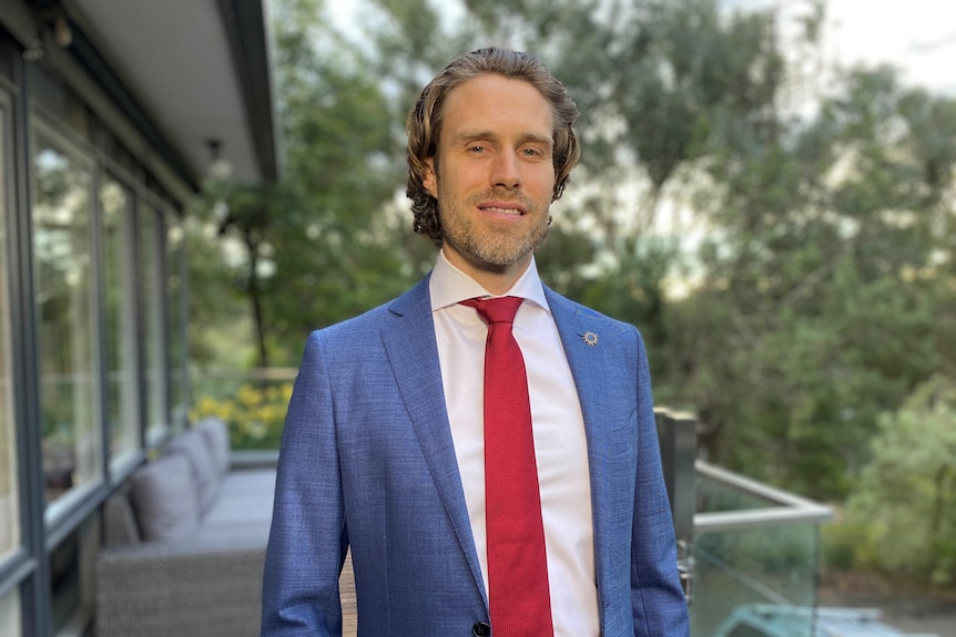 a man in a suit smiling on a balcony