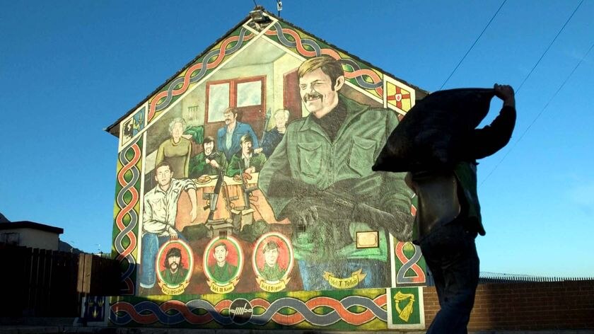 A man walks past a mural dedicated to IRA volunteers
