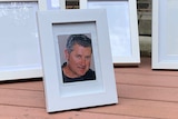 A framed photograph of Andrew Witt sits in front of four empty photo frames.
