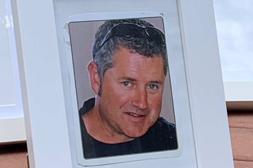 A framed photograph of Andrew Witt sits in front of four empty photo frames.