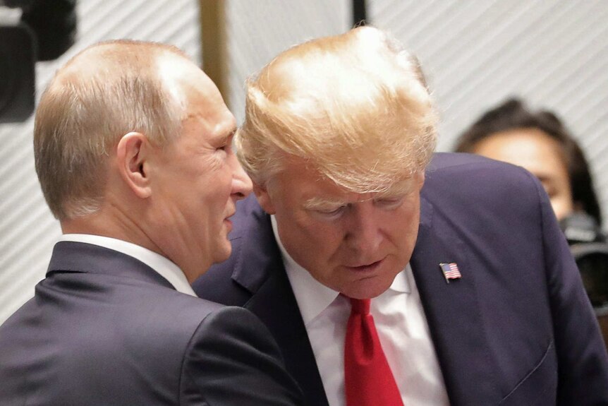Russian President Vladimir Putin smiles as he speaks into US President Donald Trump's ear.