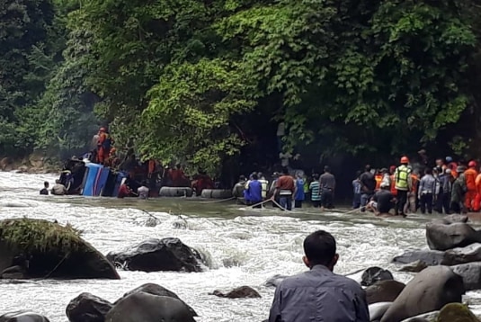 In the distance, you view a line of rescuers who hold a rope in a fast-flowing river trying to reach a blue bus submerged.