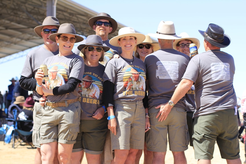 A group of men and women in khaki pose for a shot at the Birdsville Races.