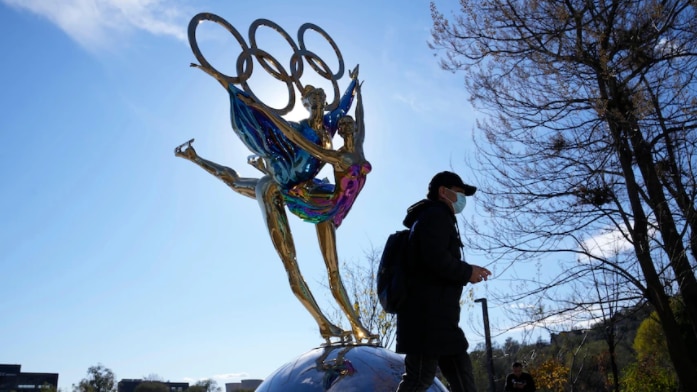 A man walks past a statue for the Winter Olympics.