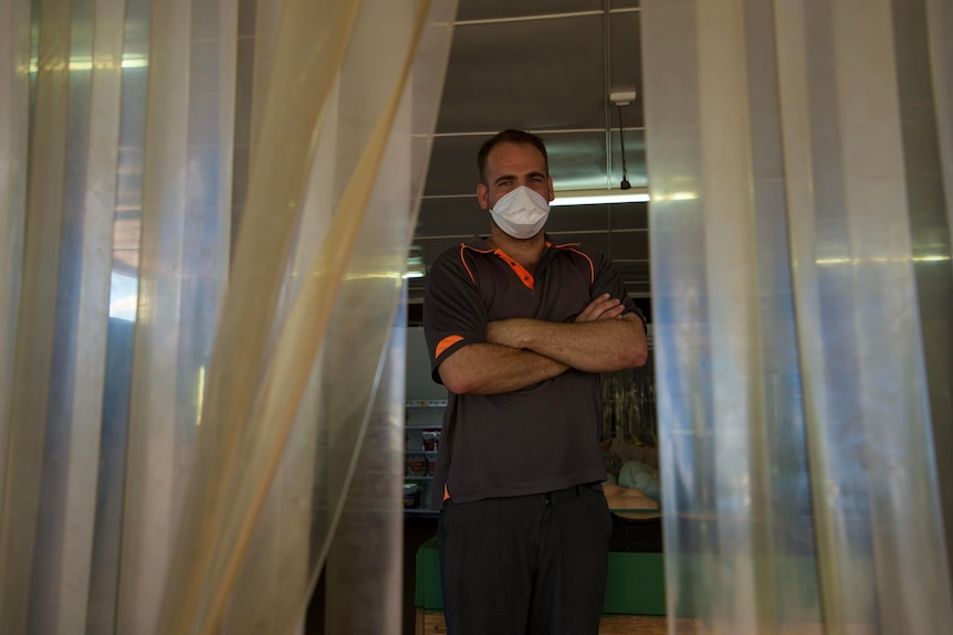 Man standing with arms crossed in door frame