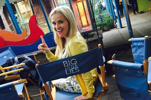 A smiling blonde woman sits on a chair ina  film studio