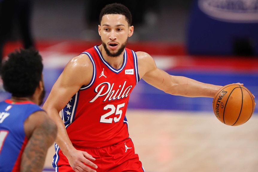 Ben Simmons dribbles the ball with his left hand while sizing up a defender in front of him