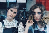 Two young women look through window