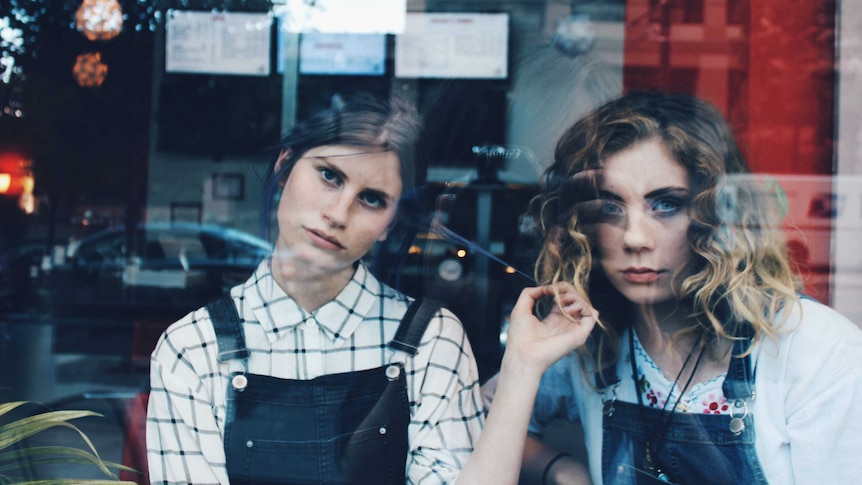 Two young women look through window
