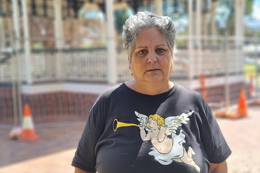 A woman stands wearing a t-shirt with an angel on it.