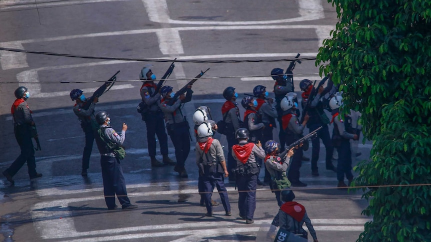 A group of 17 armed police point rifles up toward the same target