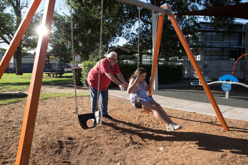 David pushing his daughter Kali on a swing at the local playground