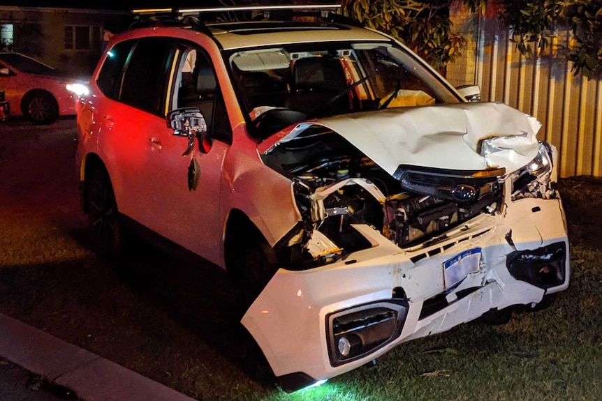 A smashed white Subaru Forester SUV at night.