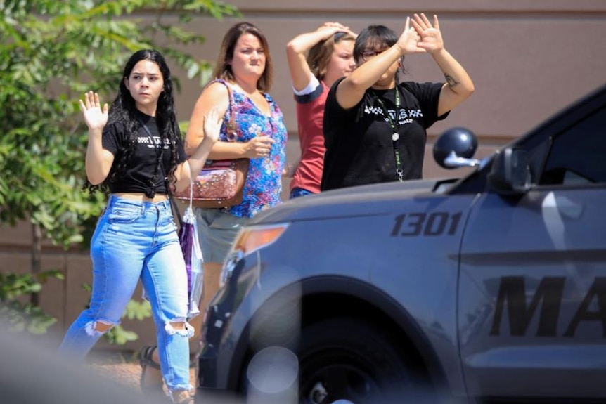 four people walk along with their hands raised