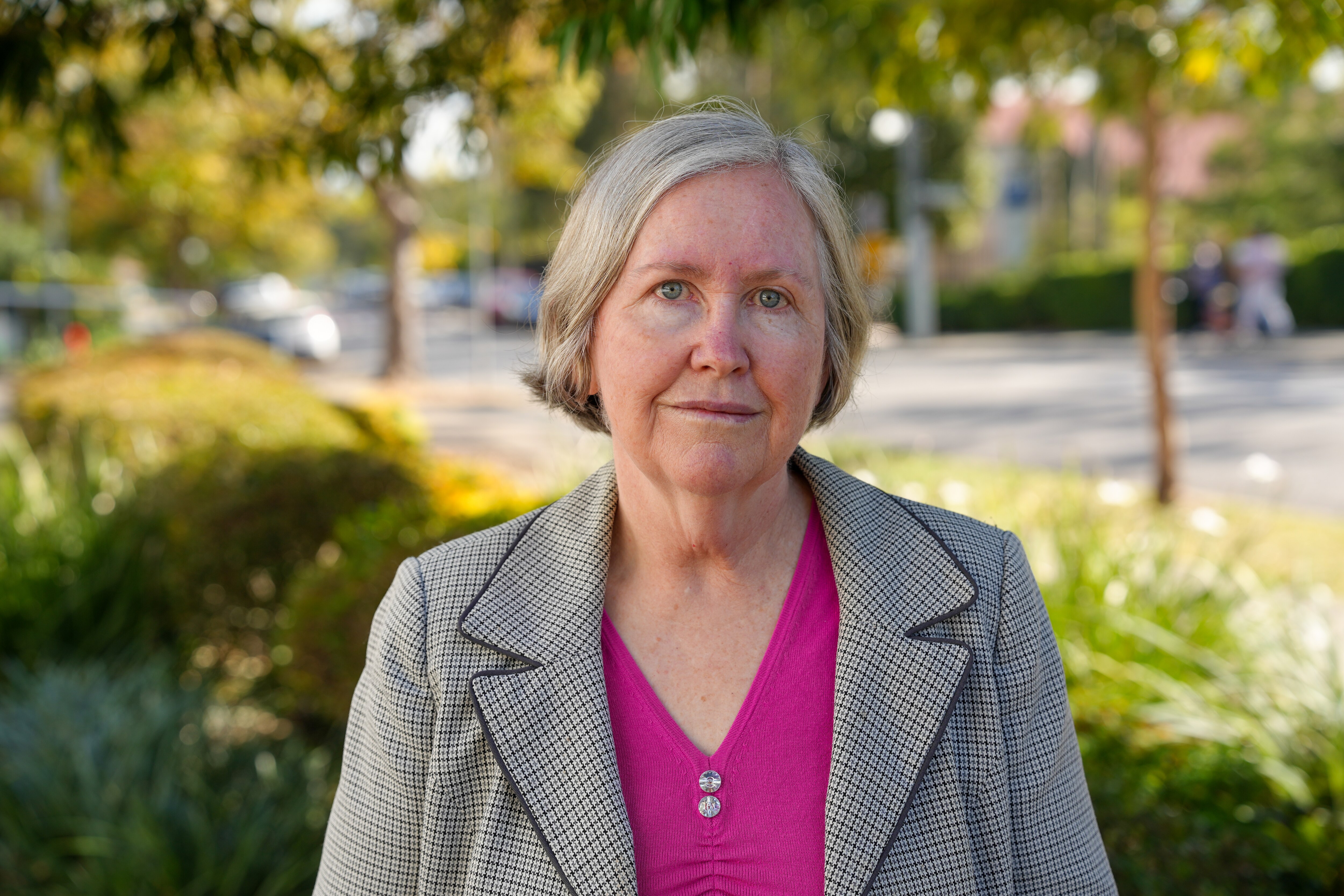 A portrait of a woman with short hair wearing a pink shirt and blazer.