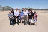 Menindee locals and politicians pose for a photo standing in the centre of an unsealed road near Menindee.