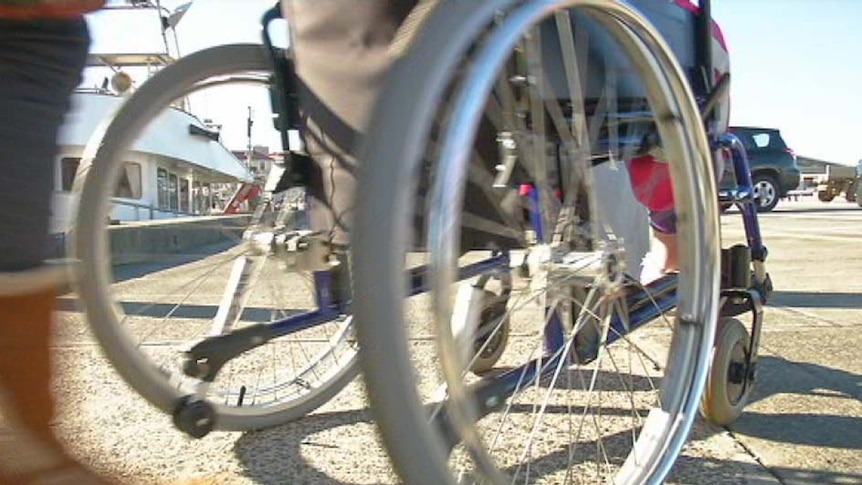 A carer pushes a wheelchair on Hobart waterfront.