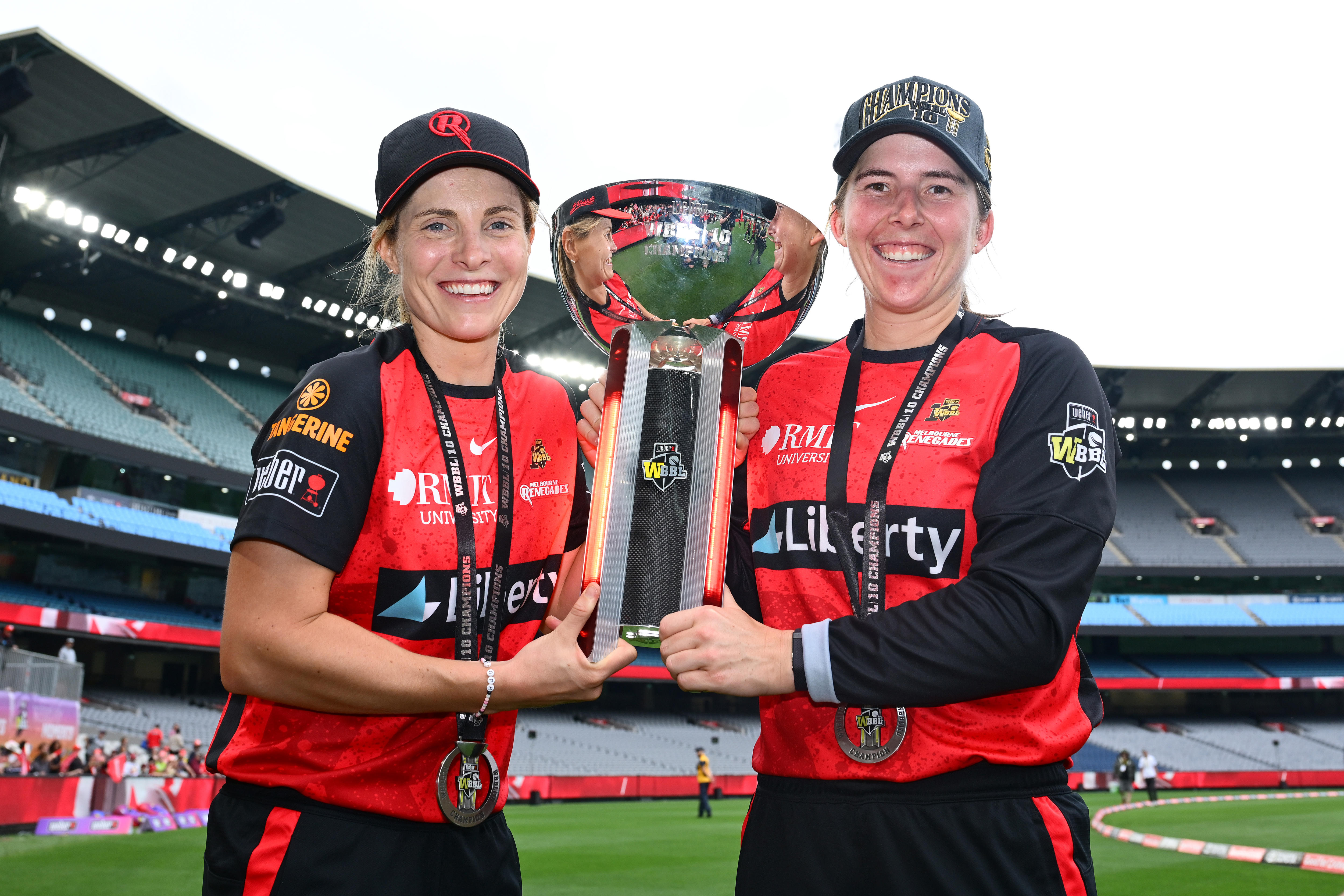 Two players hold a trophy and smile