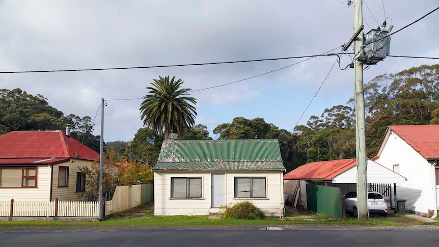 A stand alone run down house against a bush backdrop