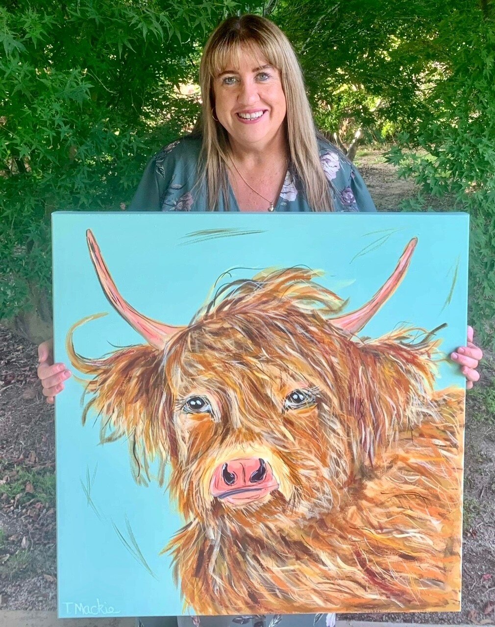 Picture of Tracey Mackie holding painting of Cow titled Catriona