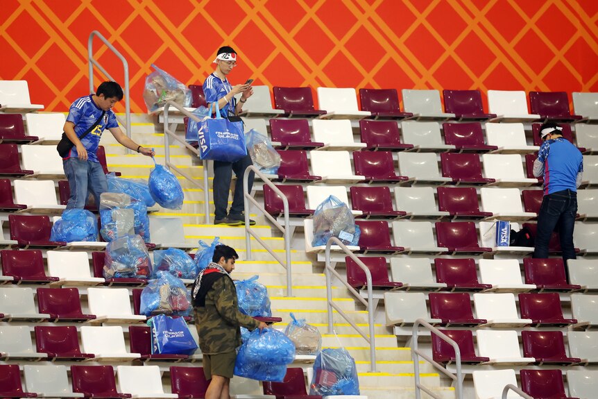 Japan supporters hold blue rubbish bags in the stands of a stadium