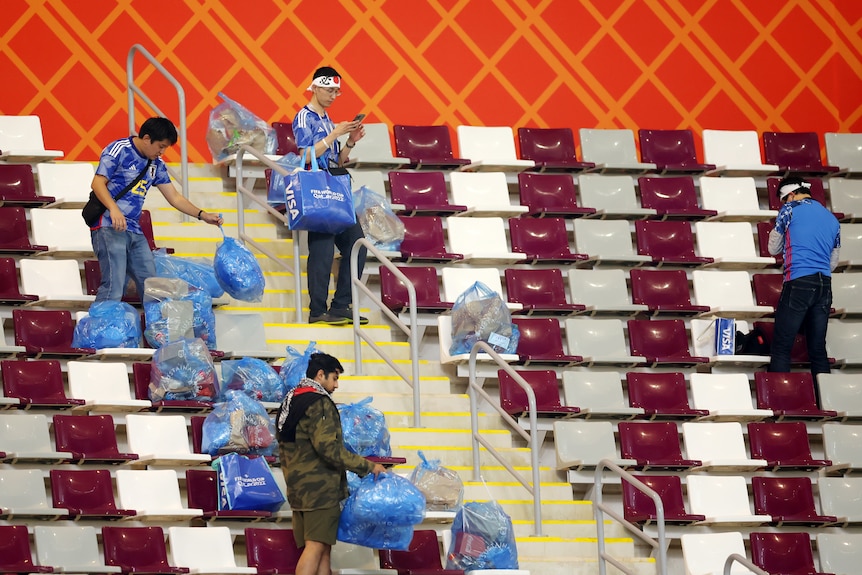 Japan supporters hold blue rubbish bags in the stands of a stadium
