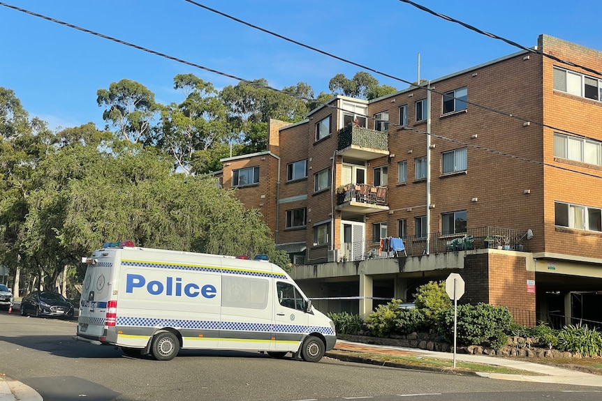 A police van is parked outside a block of units.