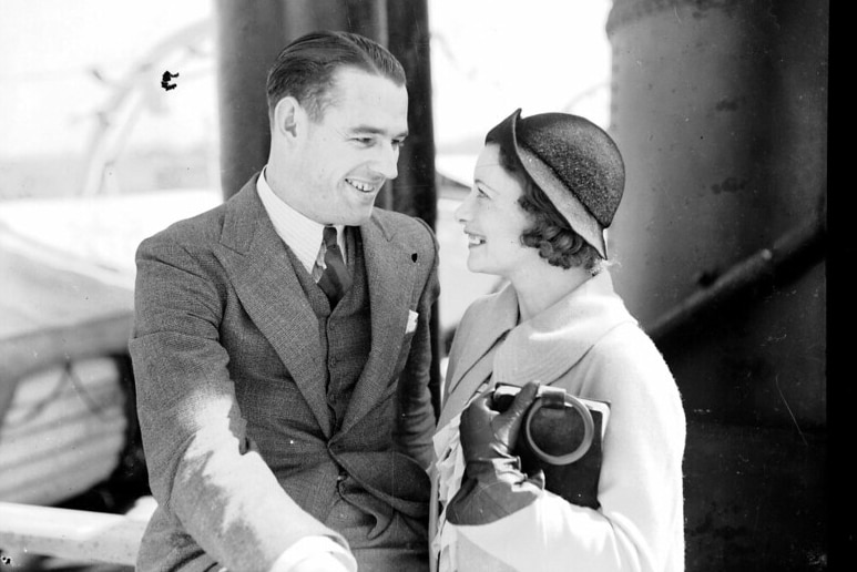 A 1930s photo of a man and woman in smart clothing, smiling at each other.