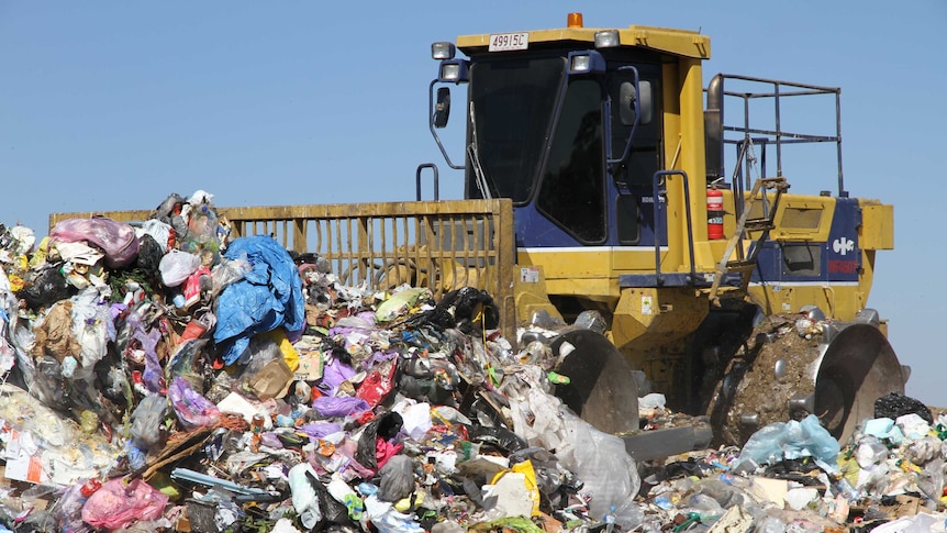 rubbish compactor pushing a pile of waste