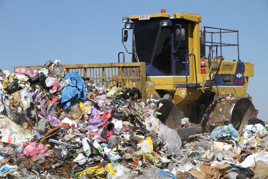 rubbish compactor pushing a pile of waste