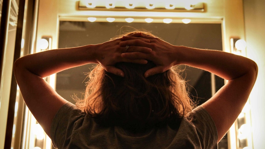 Back of woman's head in a lit up dressing room.