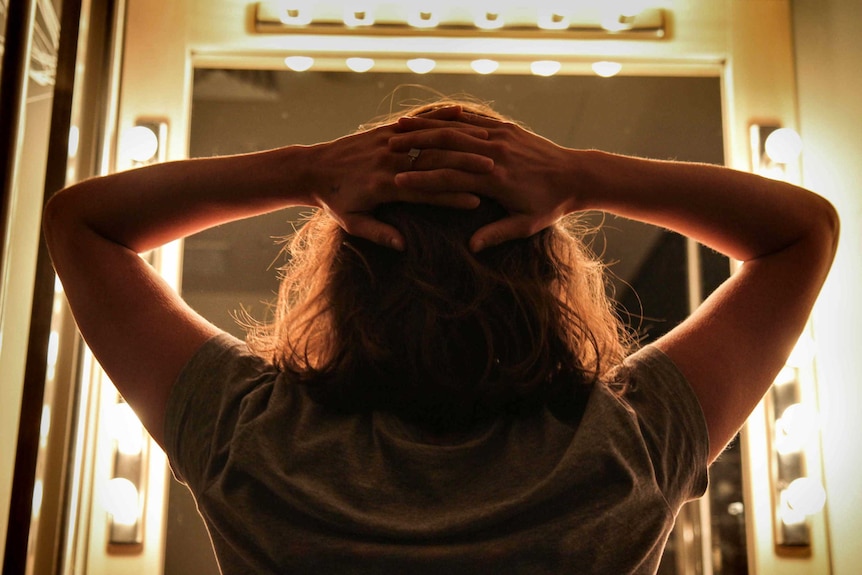 Back of woman's head in a lit up dressing room.