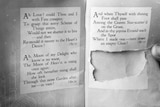 A black and white photo of a book with a section torn out.