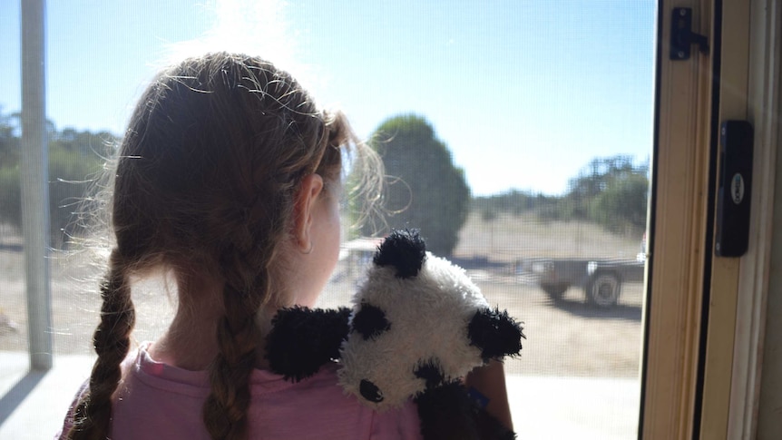 A girl with pigtails hugs her toy.