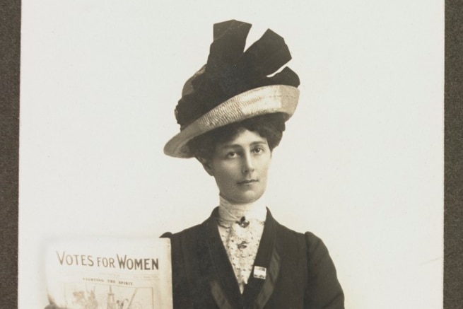 Old style photograph of first wave feminist woman holding a newspaper called 'Votes for Women'